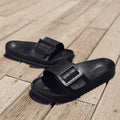 Women's grey blue buckle flip-flop slippers on a light background, showing adjustable strap and cushioned sole.