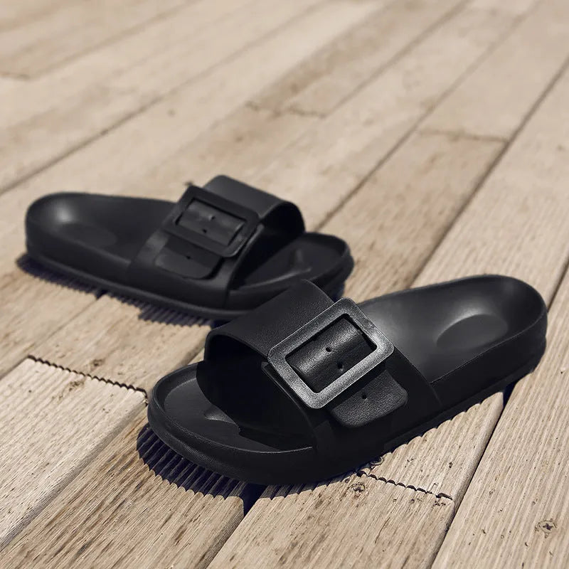 Women's grey blue buckle flip-flop slippers on a light background, showing adjustable strap and cushioned sole.