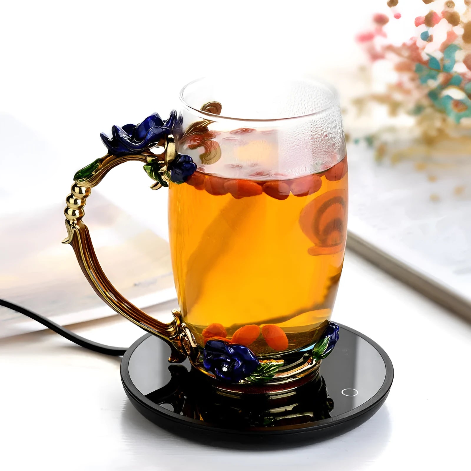 Black coffee cup warmer pad with temperature switch on a desk next to a mug.
