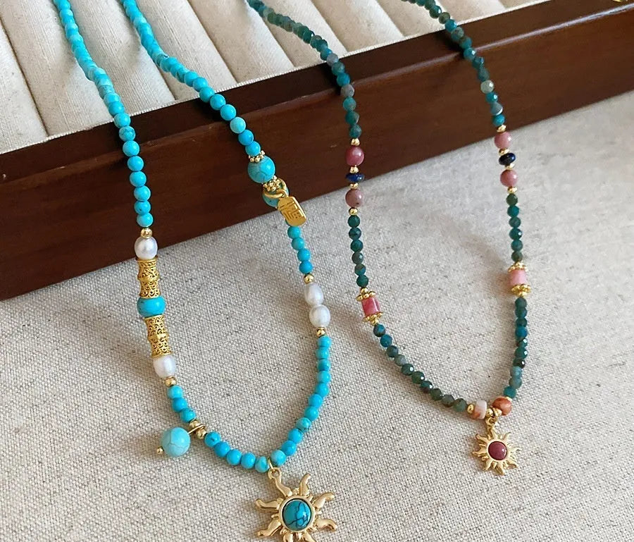 Freshwater pearl necklace with a blue stone sun pendant on a delicate clavicle chain.