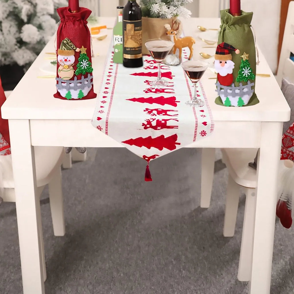 Red, white, and green Christmas table runner with elk and snowman print on a wooden dining table.