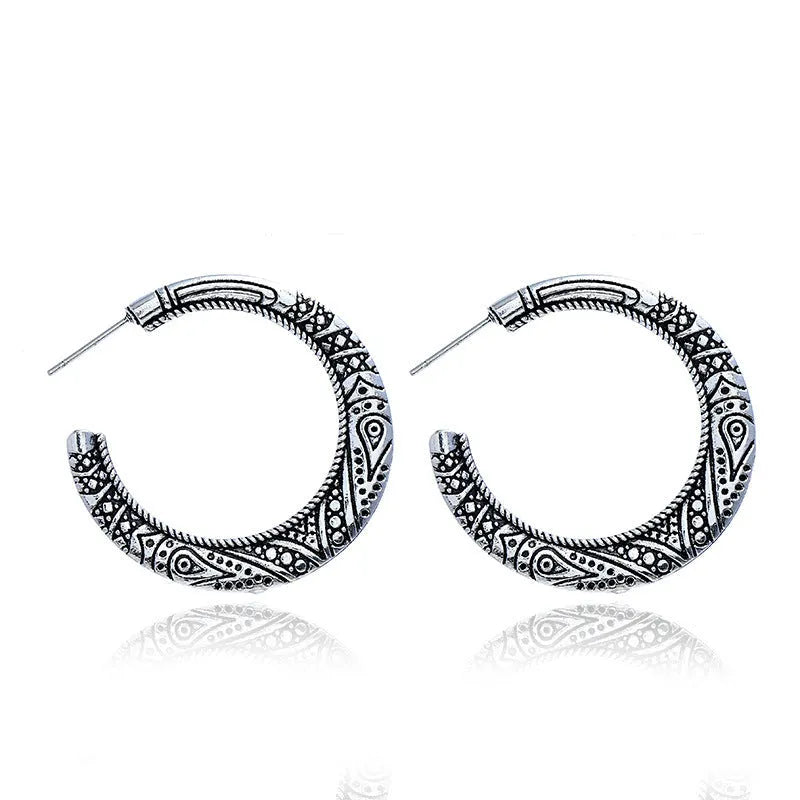 Pair of bronze C-shaped alloy earrings with detailed vintage engraving on the surface.