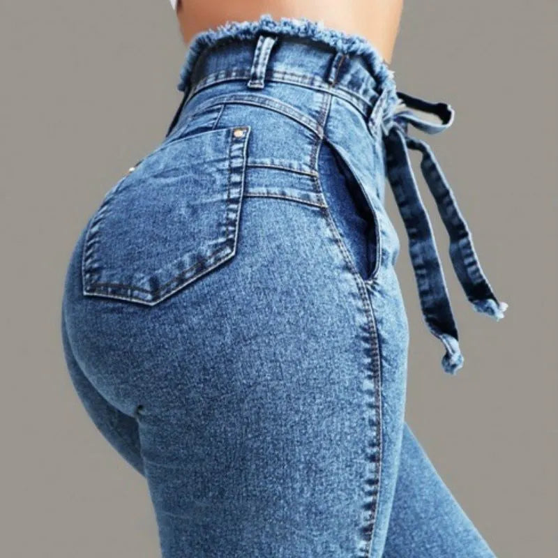 A pair of light blue fringed jeans with a distressed hem laid flat.