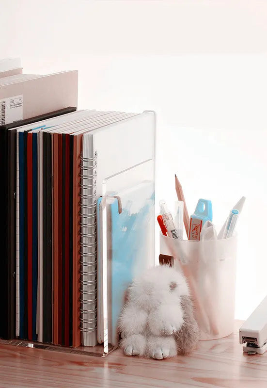 Clear transparent acrylic bookshelf holding a small number of books on a desk
