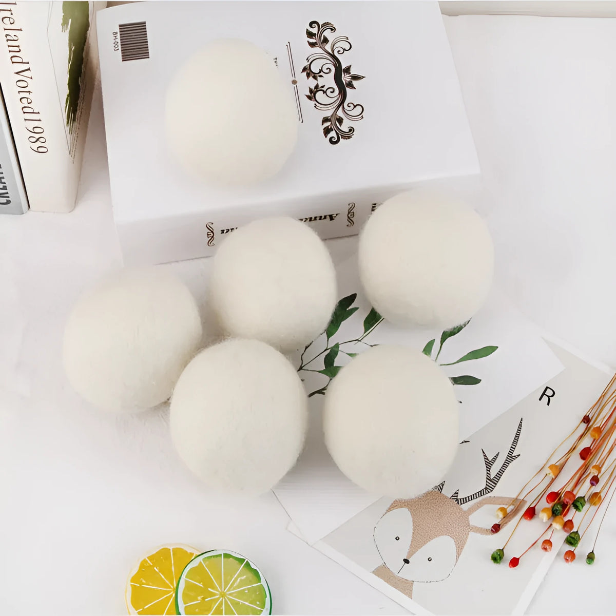 Set of 100% wool anti-static drying balls next to a plain cotton storage bag on a laundry background.