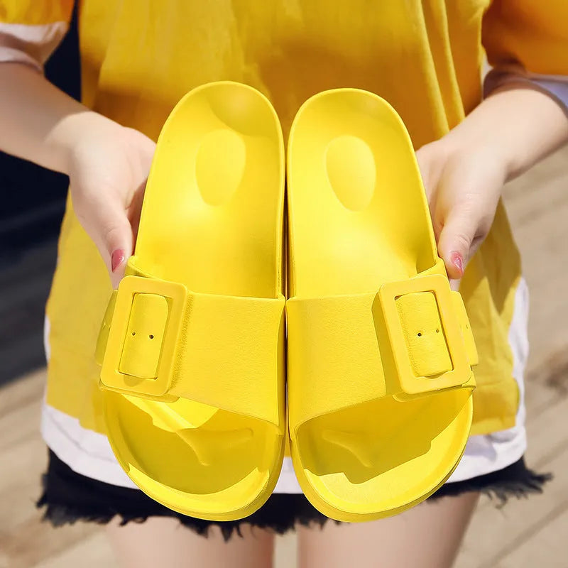 Women's grey blue buckle flip-flop slippers on a light background, showing adjustable strap and cushioned sole.