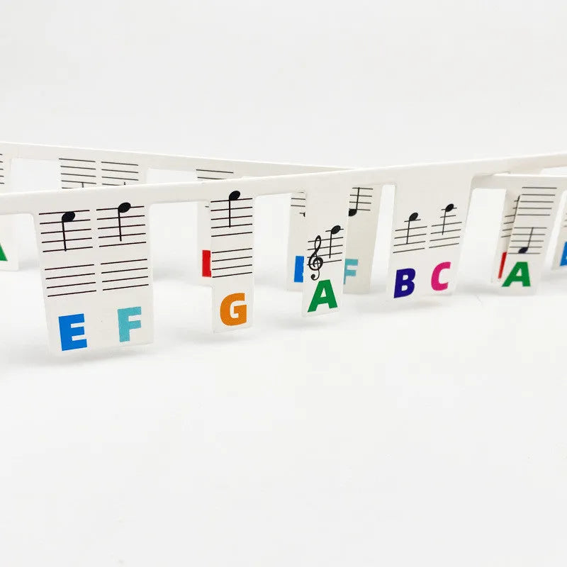 Set of 88 white cardboard piano key stickers showing staff notation and colour note bars for a full-size keyboard.