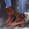 Women's blue cowboy boots with embroidery, wedge heel, and pointed toe on a neutral background