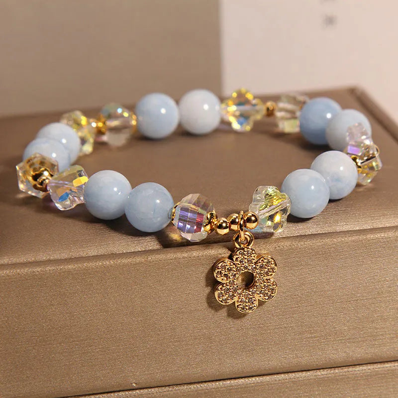 Aquamarine crystal and pearl bracelet with four-leaf clover charm on wrist.