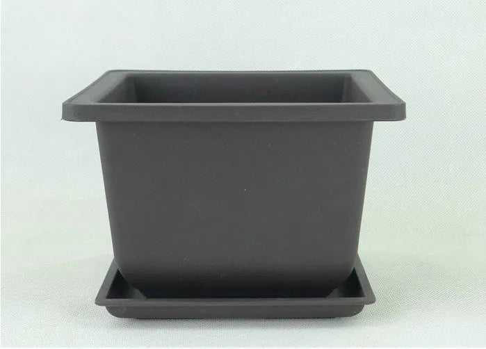 Dark brown antique-style recycled plastic flowerpot on a wooden garden table.