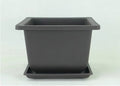 Dark brown antique-style recycled plastic flowerpot on a wooden garden table.