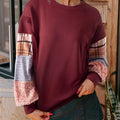 Women's beige and red plaid stitch long-sleeved loose pullover top on a hanger.