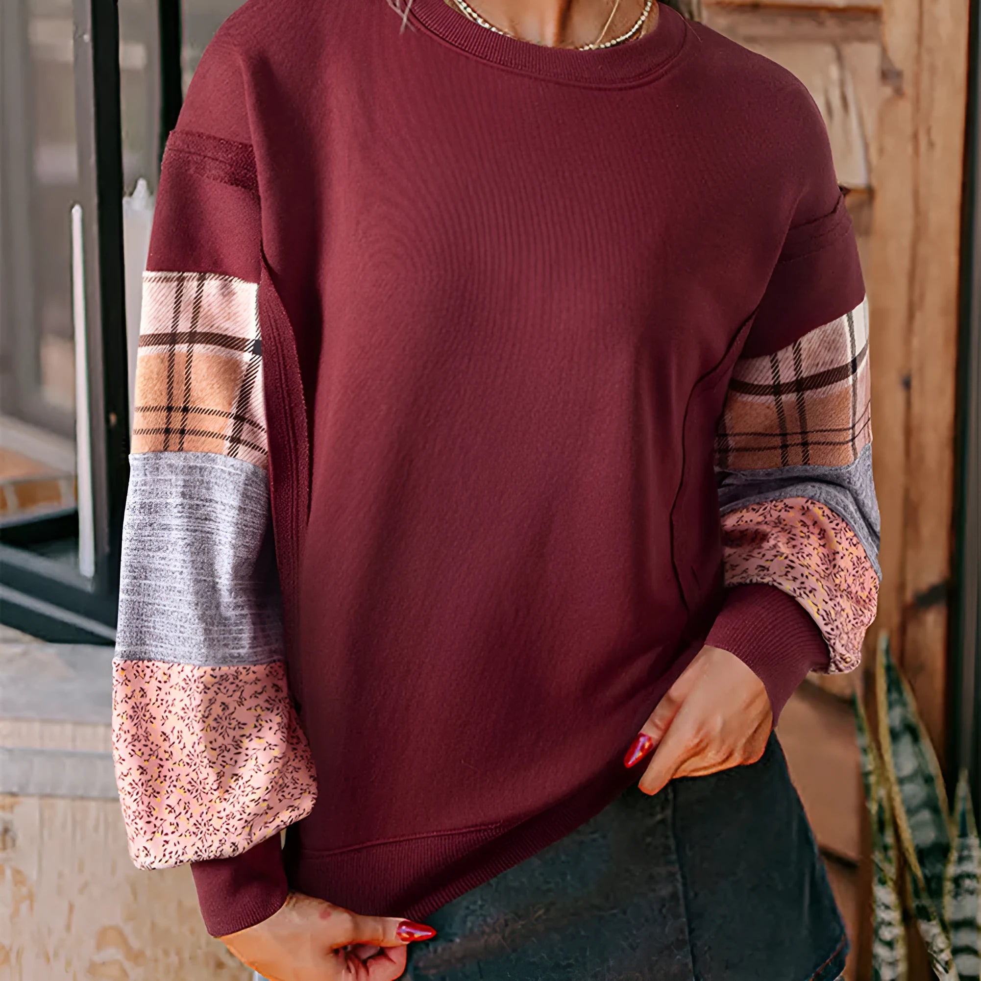 Women's beige and red plaid stitch long-sleeved loose pullover top on a hanger.
