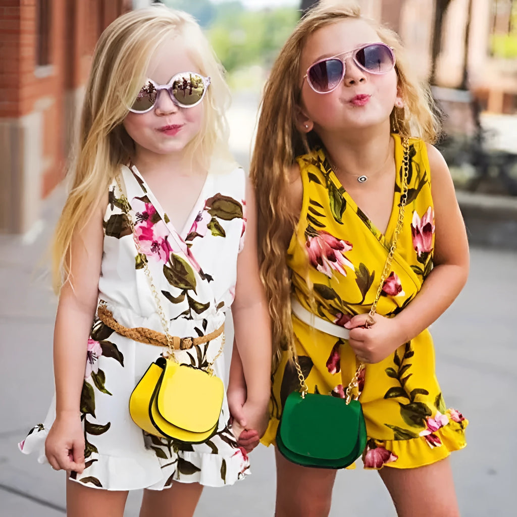 Baby girl wearing a white cotton floral romper suit with ruffle sleeves and bloomer-style bottom.