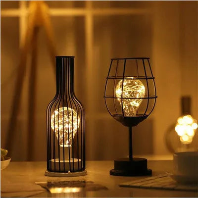 Minimalist hollow iron table lamp in a red wine bottle style with warm white LED light.
