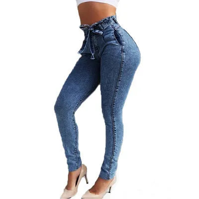 A pair of light blue fringed jeans with a distressed hem laid flat.