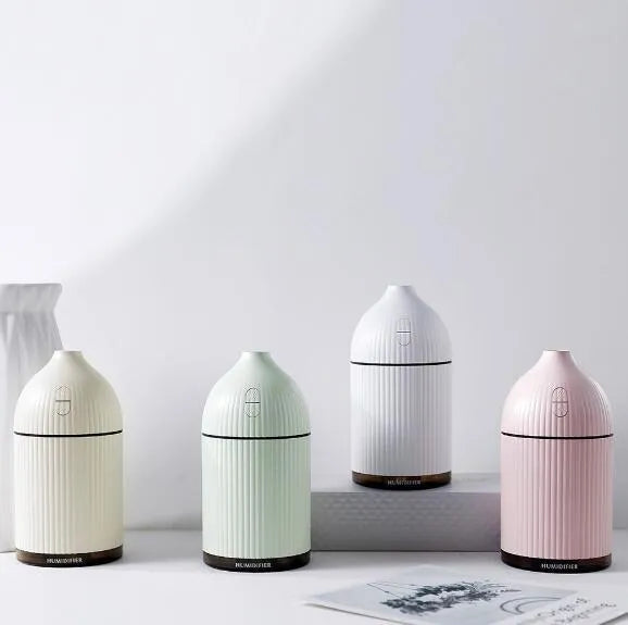 White ultrasonic aromatherapy diffuser with LED light, 300ml capacity, and USB cable on a wooden table