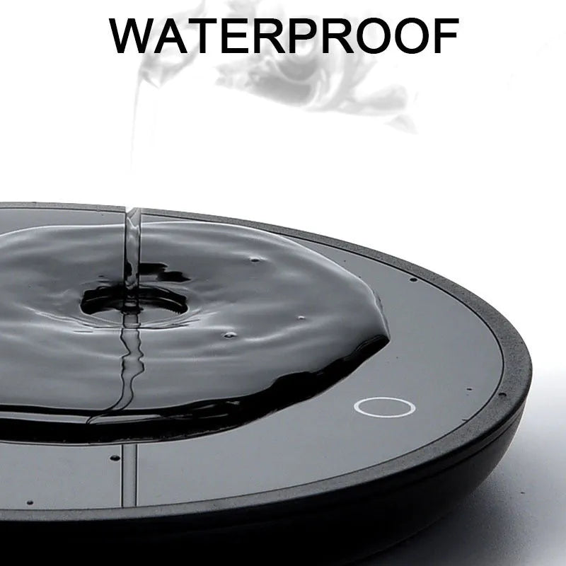 Black coffee cup warmer pad with temperature switch on a desk next to a mug.