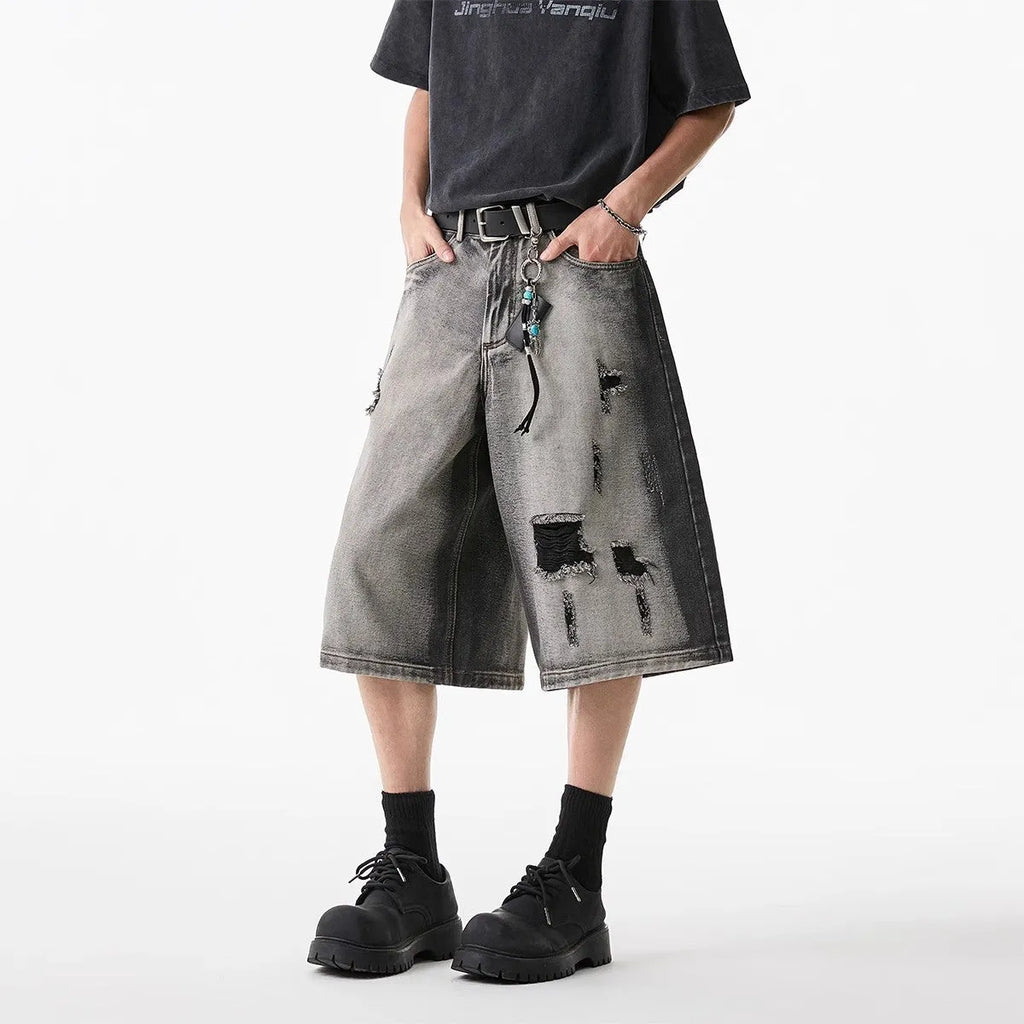 Grey denim shorts with washed finish and hole details, loose fit cropped length