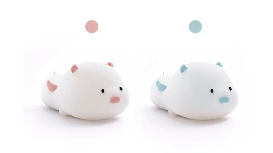 Cute pink silicone pig night light with sleeping design on a bedside table.