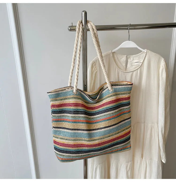 Blue straw woven large capacity shoulder bag with adjustable strap on a neutral background