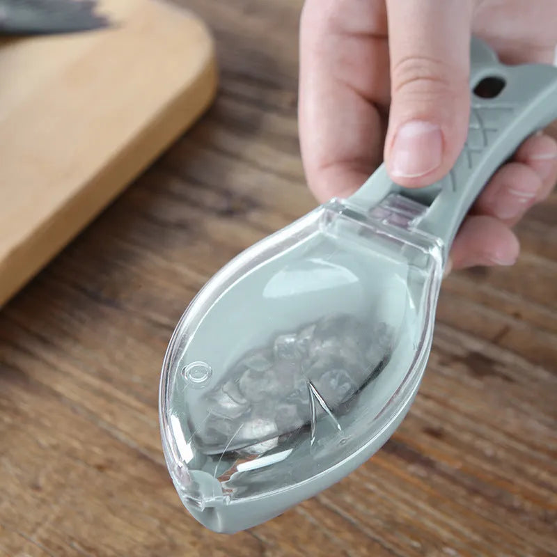 White fish-shaped kitchen scaler tool with a cover and hanging hole on handle
