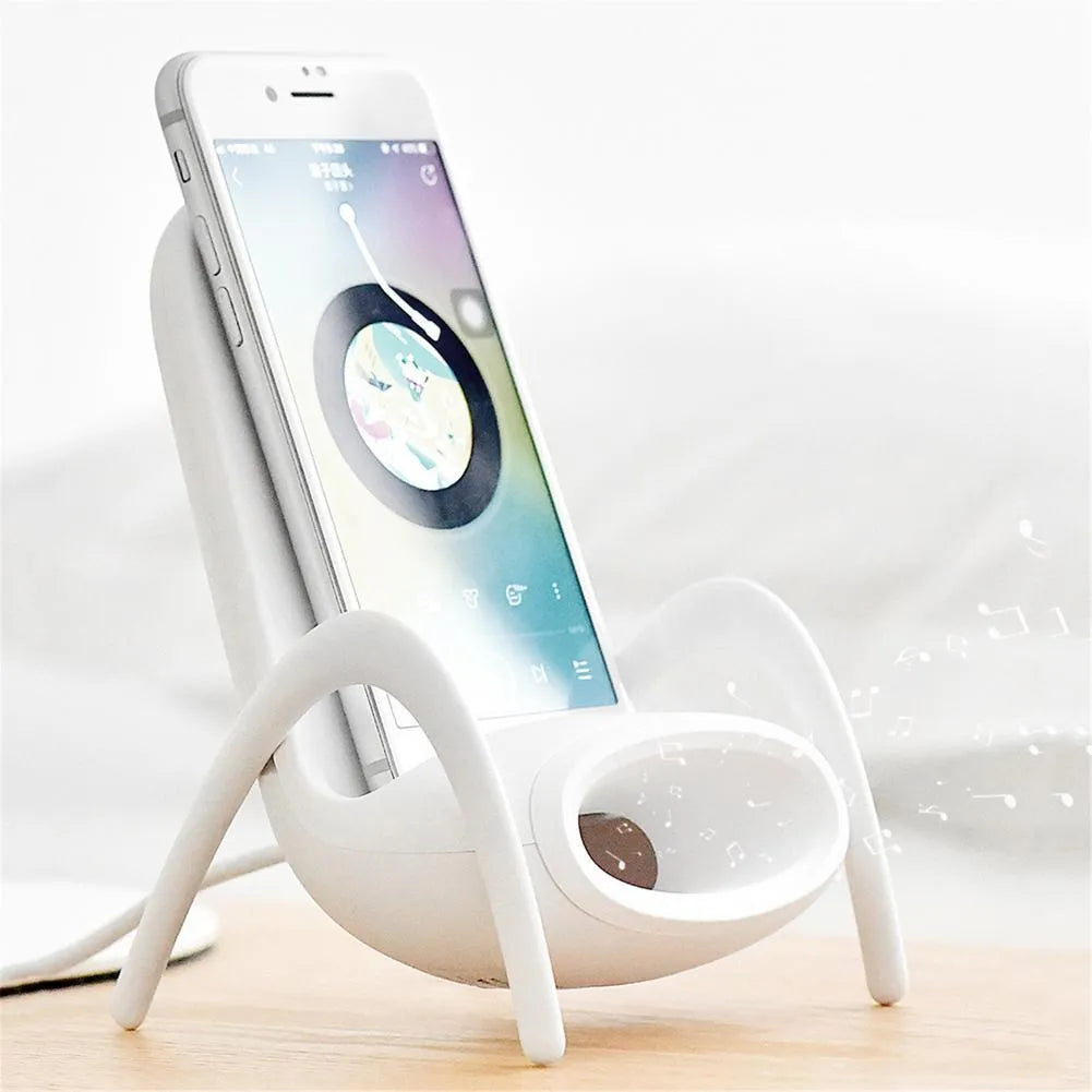 White mini chair shaped wireless charging stand holding smartphone on desk