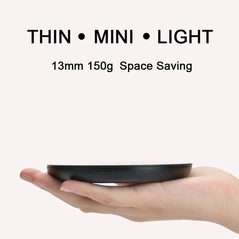 Black coffee cup warmer pad with temperature switch on a desk next to a mug.