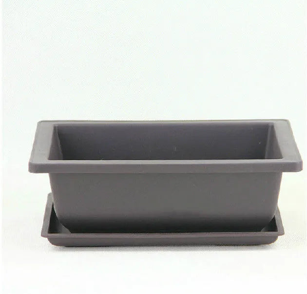 Dark brown antique-style recycled plastic flowerpot on a wooden garden table.