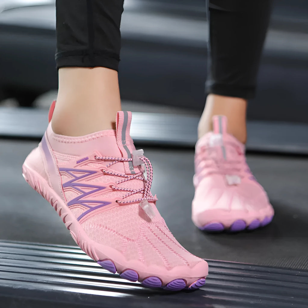 Low-top black and grey indoor training sneakers with mesh upper and rubber sole on a gym floor.