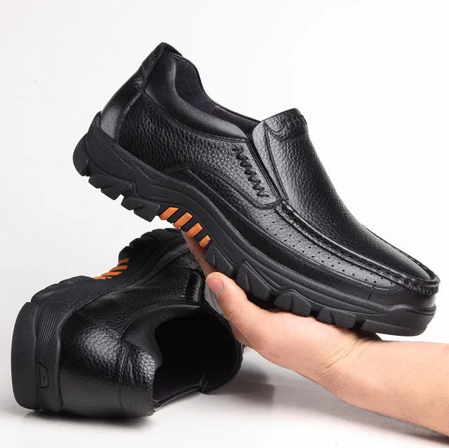 Black and brown leather business casual slip-on shoes with rubber outsoles on wooden floor