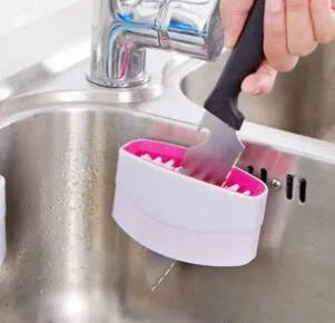 Coloured kitchen brush with knife and fork design and a white suction cup on its handle.