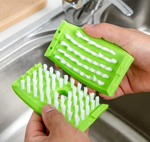 Coloured kitchen brush with knife and fork design and a white suction cup on its handle.