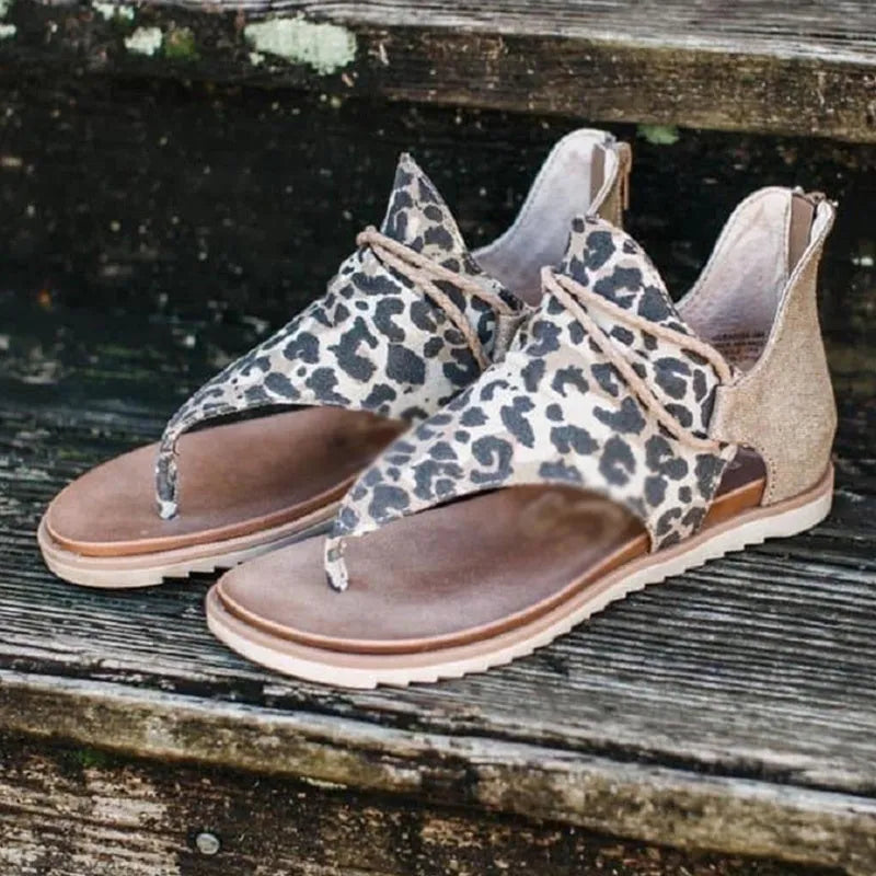 Women's flat sandals with adjustable ankle strap and open toe, shown in multiple colours including black, brown, and leopard print.