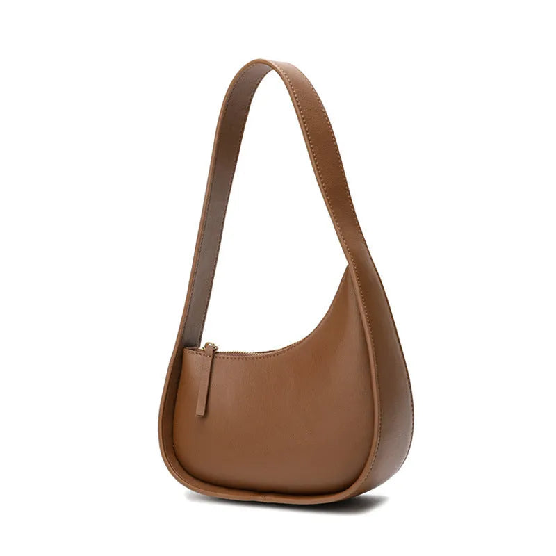 Leather ladies handbag in half-moon shape with wide shoulder strap and zipper opening