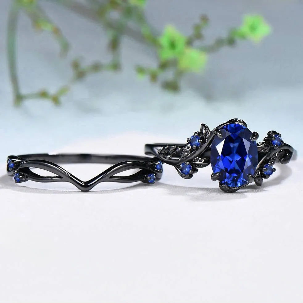 Gun black and navy blue rhinestone geometric couple ring for women on a plain background.