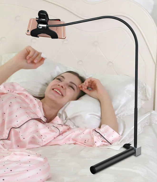 Black bedside mobile phone bracket with universal clamp mounted on a bed frame.