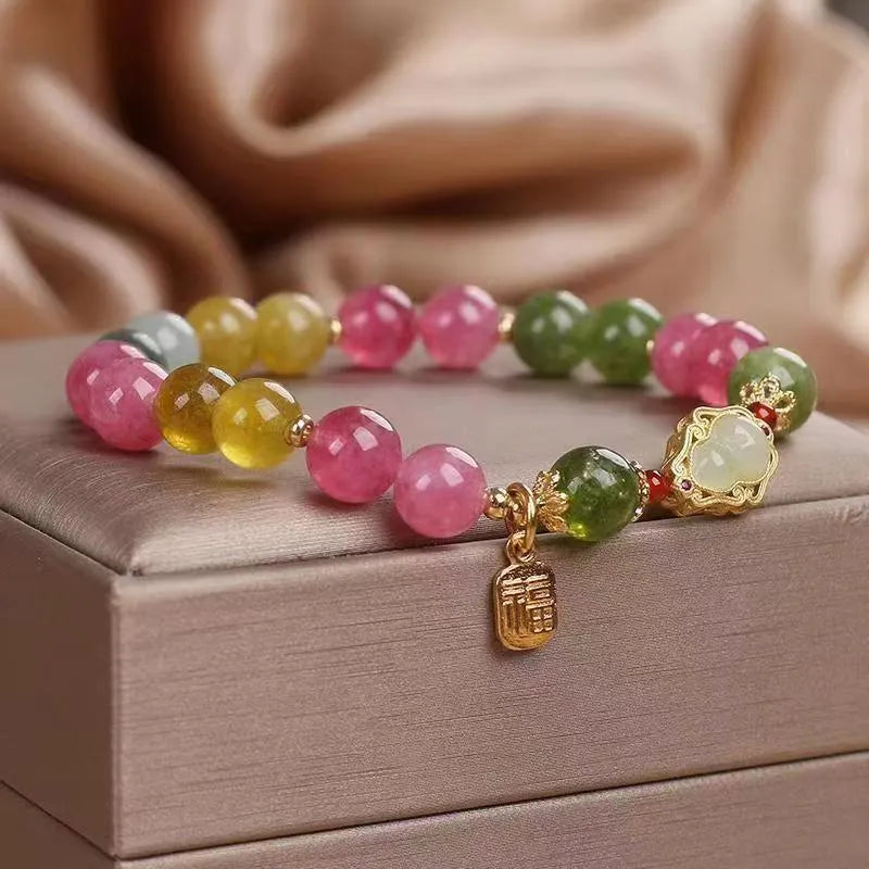 Close-up of a women's bracelet with a colourful tourmaline gourd charm and electroplated floral links.