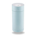 A compact white folding bracket USB humidifier on a desktop next to a laptop, showing its mist output.