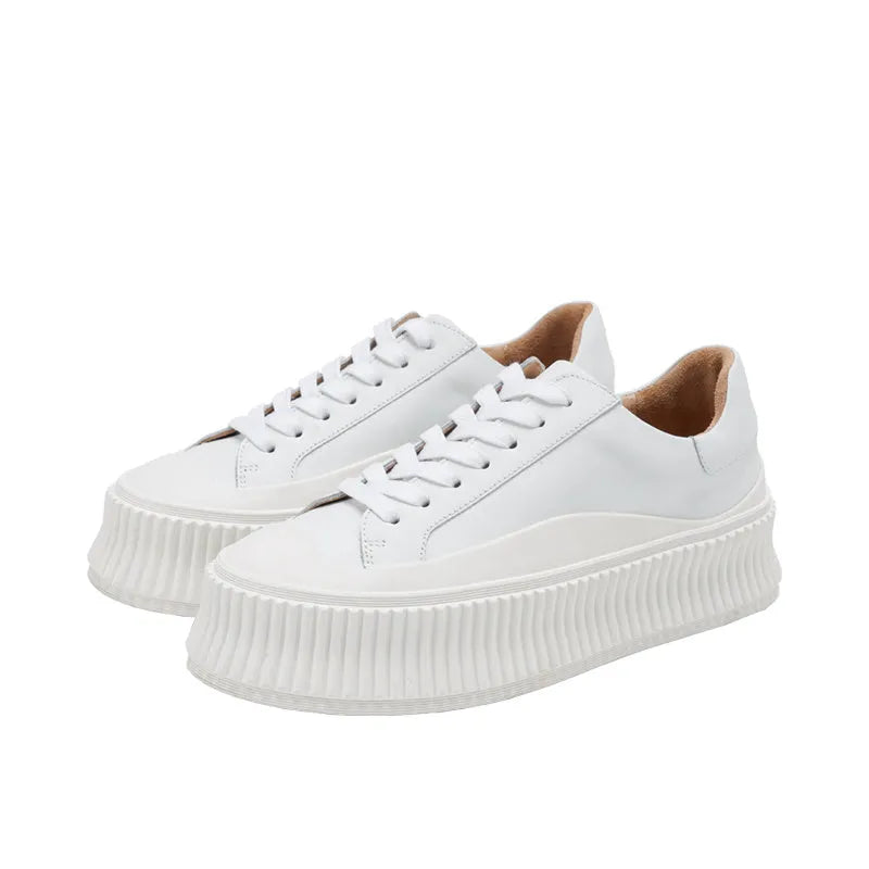 Women's mid-top platform sneakers with suede upper, thick sole, and lace-up design in black and white colours.