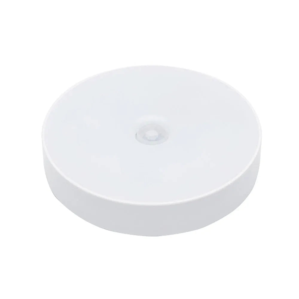 White circular LED motion night light with USB charging port, 86mm diameter, mounted with adhesive tape