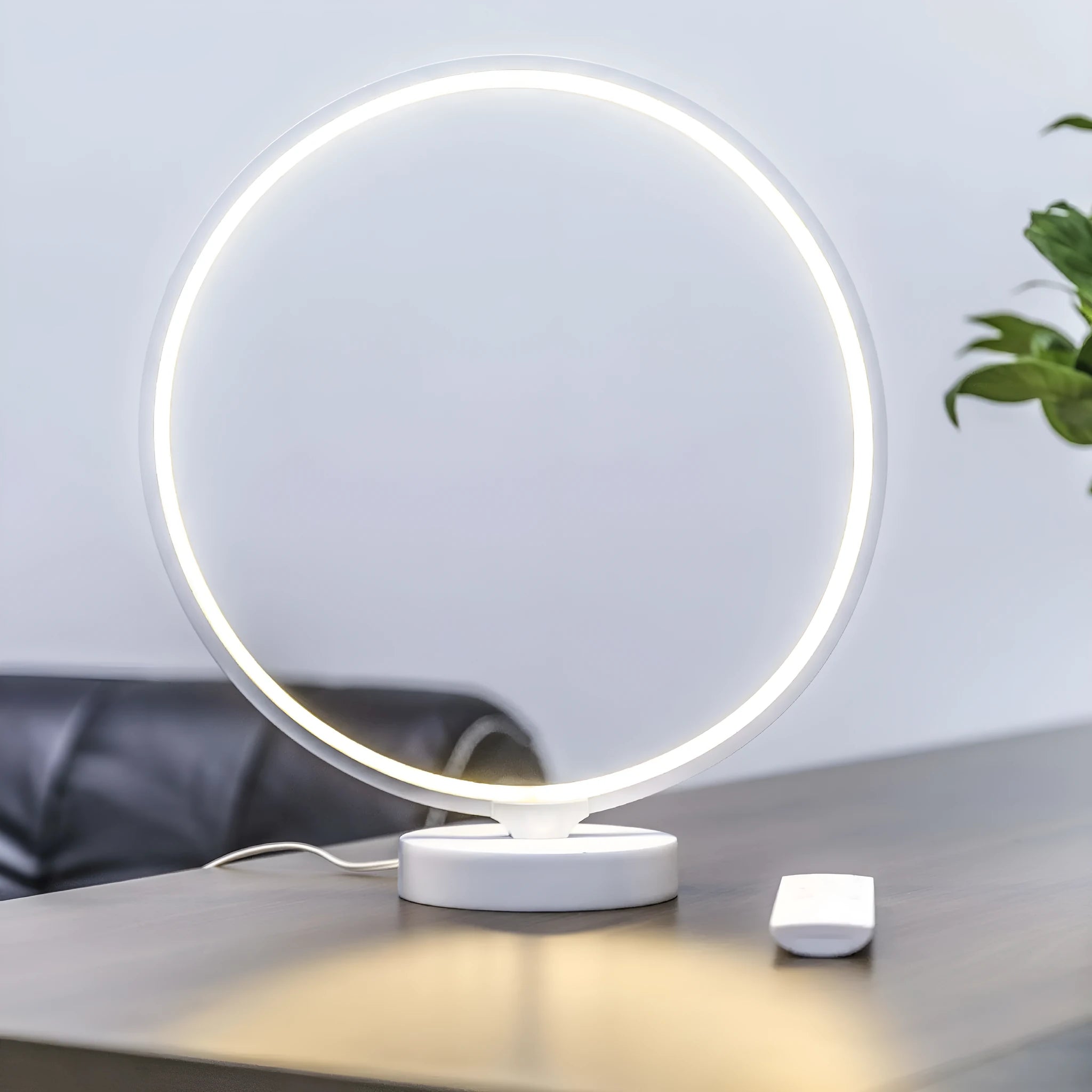 White Full Moon shaped table lamp with remote control on a wooden surface.