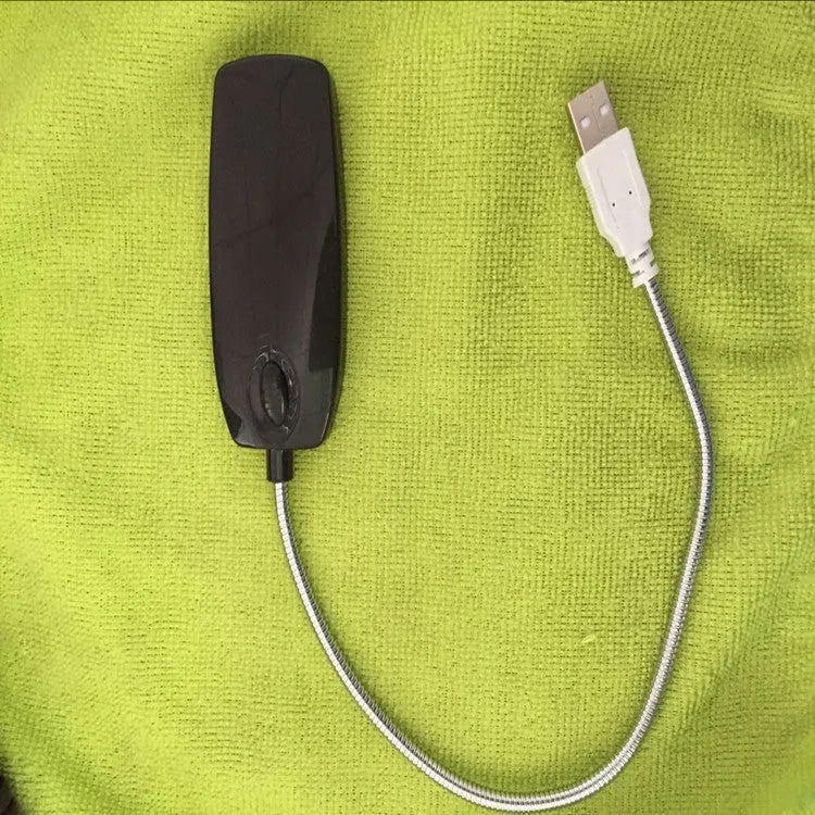 Black flexible USB desk lamp with LED light bent over a laptop keyboard.