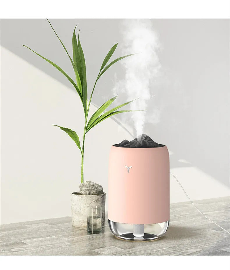 White columnar magic flame humidifier and aroma diffuser on a desktop with mist and coloured light effect.