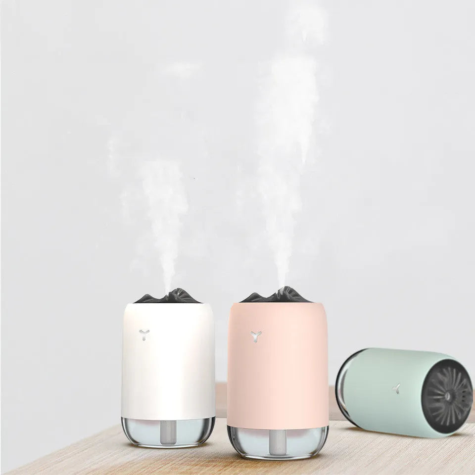 White columnar magic flame humidifier and aroma diffuser on a desktop with mist and coloured light effect.