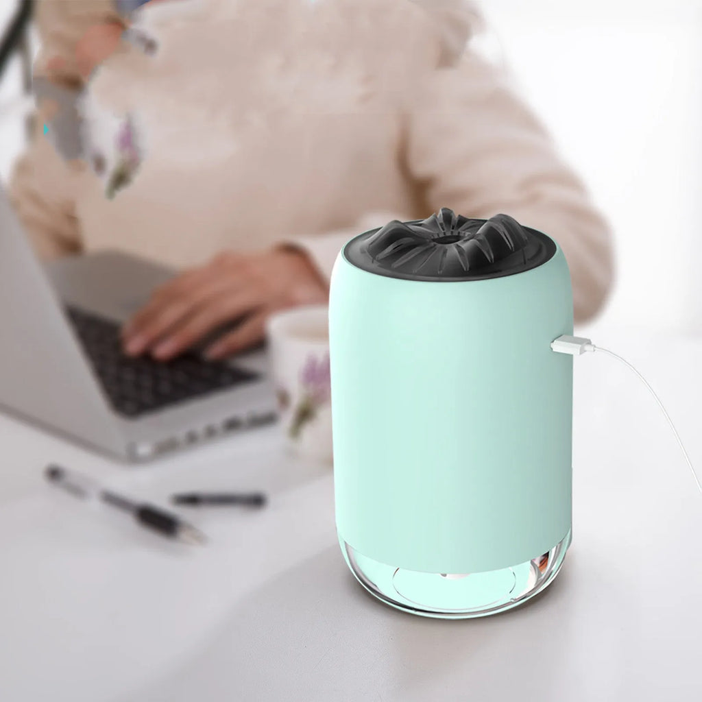 White columnar magic flame humidifier and aroma diffuser on a desktop with mist and coloured light effect.