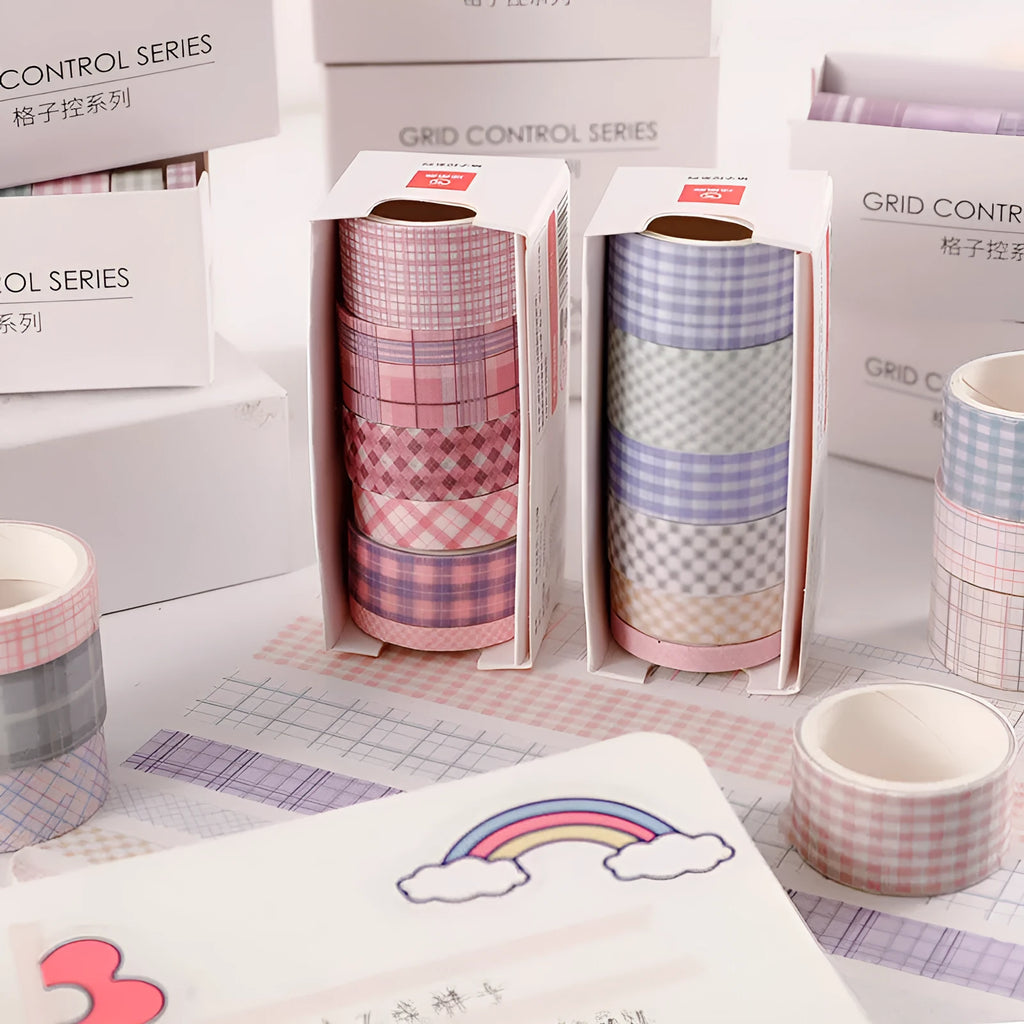 Set of six rolls of retro plaid and floral Japanese washi tape in four different widths on a craft table.