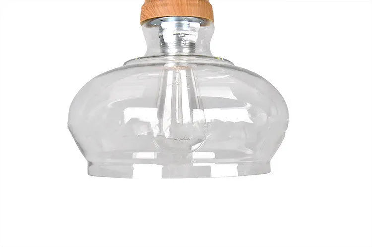 Single head glass pendant light with wood grain finish hanging from ceiling on adjustable cable.