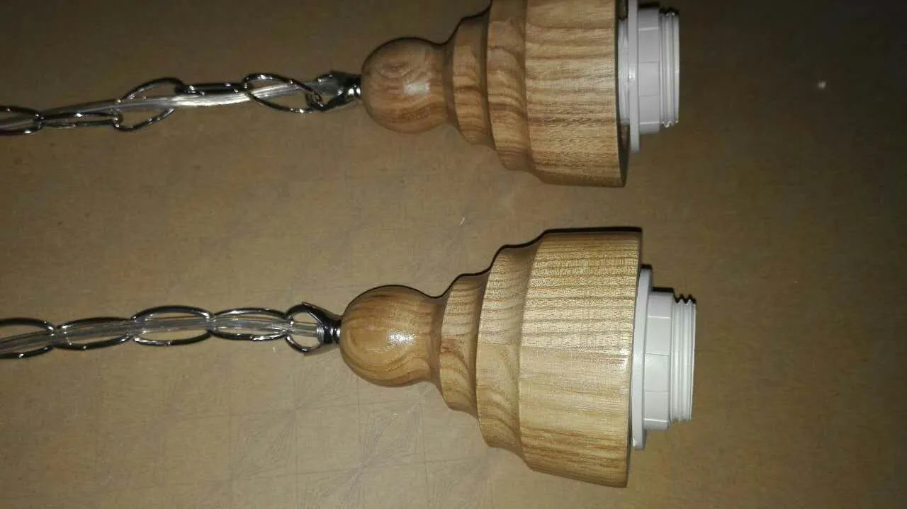 Single head glass pendant light with wood grain finish hanging from ceiling on adjustable cable.