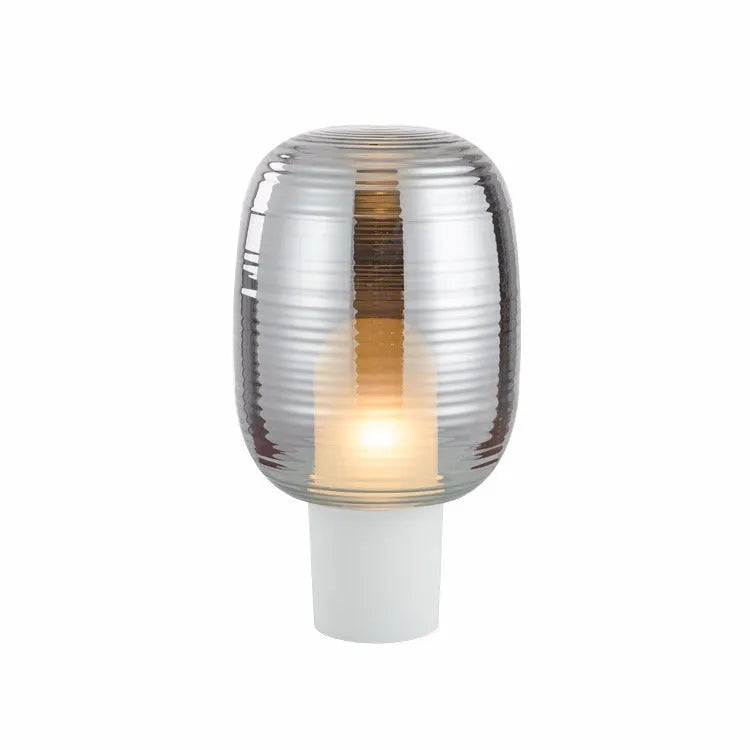 Simple modern glass table lamp on a table, shown in cognac and smoky grey colour options.